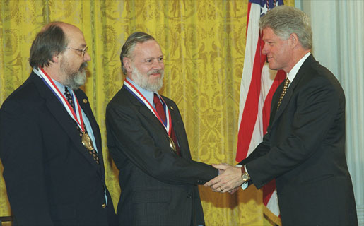 Ken Thompson (izq) y Dennis Ritchie (centro) recibiendo la Medalla Nacional de Tecnología en 1998 de manos del entonces presidente Bill Clinton (der). Fuente: Wikipedia